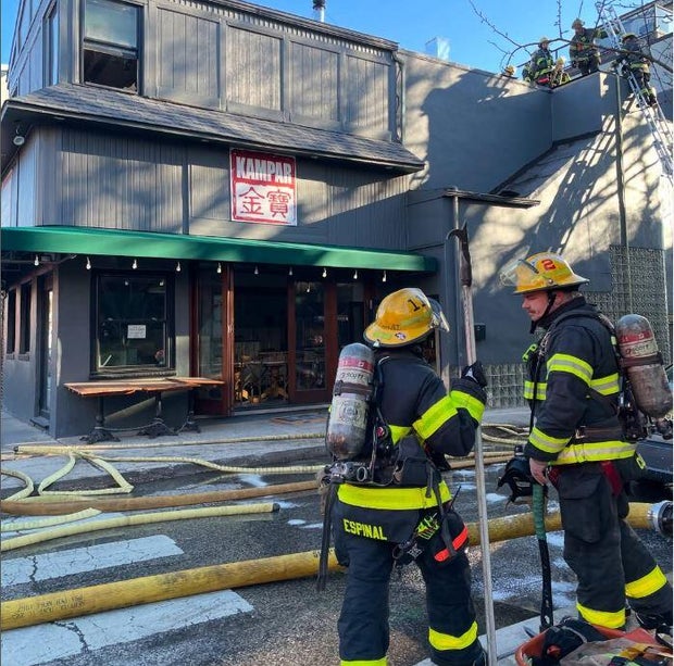 Firefighters stand in front of Kampar after the fire