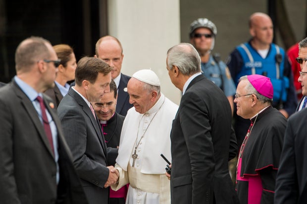 Surrounded by people, Pope Francis shakes a man's hand 