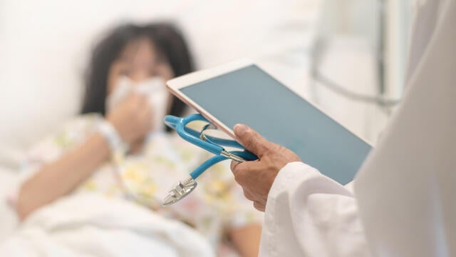 Professional general medical pediatrician doctor in white uniform gown visit Asia child patient with stethoscope and tablet computer chart. Physician check up Asian kid female inpatient in hospital children ward. 