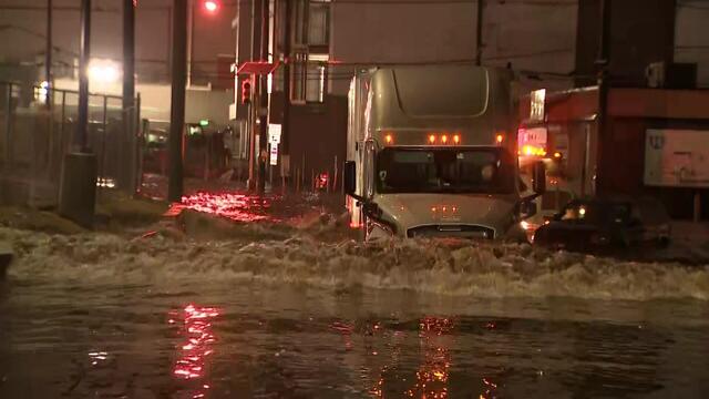 A semitruck drives through flooded streets 