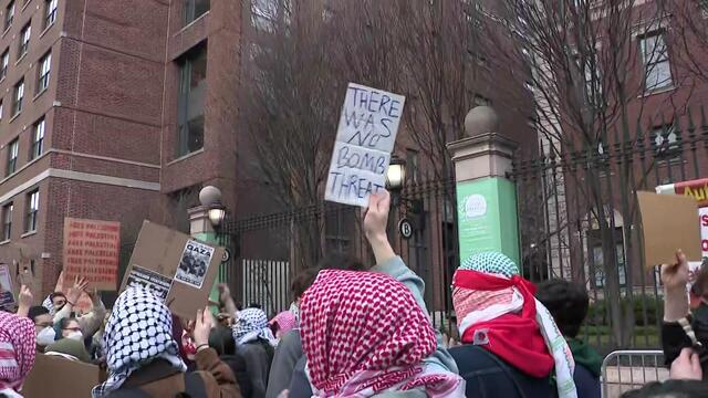 Protesters stand outside Barnard College, some holding signs, including one reading "There was no bomb threat." 