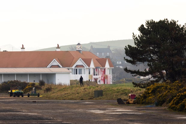A man looks at a club house covered in red paint after U.S. President Trump protests at the golf course in Turnberry
