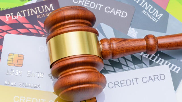 Legal proceedings in financial disputes, credit card debt settlement and financial regulation : A wooden gavel placed on top of many credit cards, depicting regulations surrounding credit and banking. 