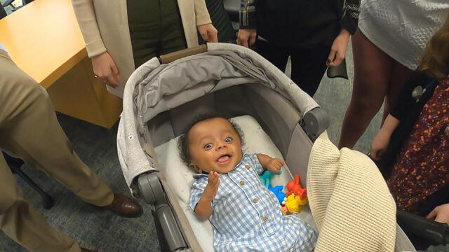 Koa smiles at the camera from his stroller 