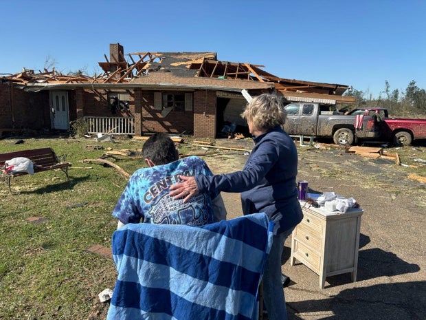 Cynthia Leake comforts Mickey Power in front of his home the day after a tornado destroyed it in Tylertown, Mississippi, March 16, 2025.