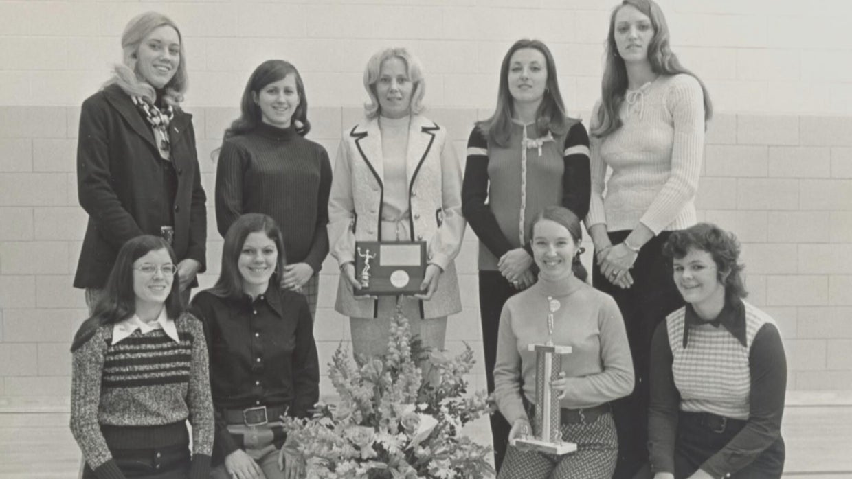The women's basketball team poses for a photo with their trophies and awards 