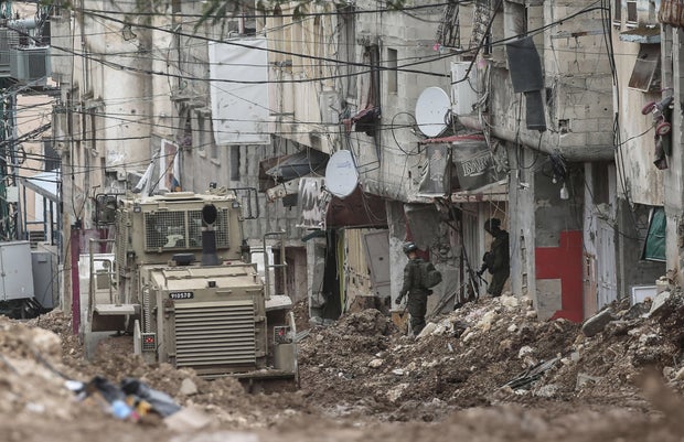 Israeli soldiers stand near a military bulldozer in the center of the Tulkarm refugee camp in the West Bank city of Tulkarm, March 22, 2025