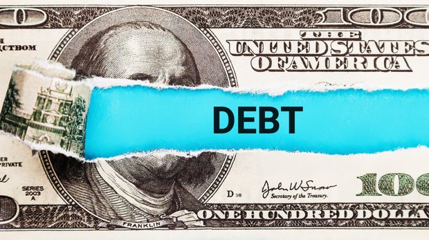 Debt. The word Debt in the background of the US dollar. Financial Burden, Loan, and Credit Concept. Stress from Financial Obligations