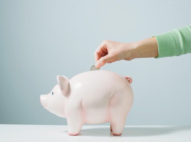 Hand placing coin in piggy bank