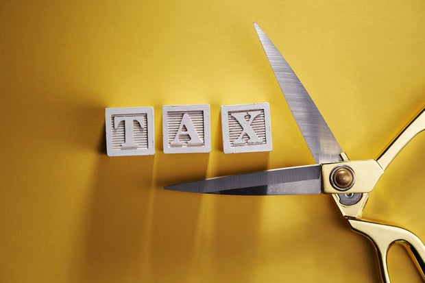 wood block with alphabet TAX and scissors on yellow background 
