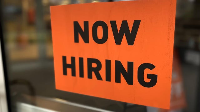 ‚Äúnow hiring‚Äù sign posted on business door 