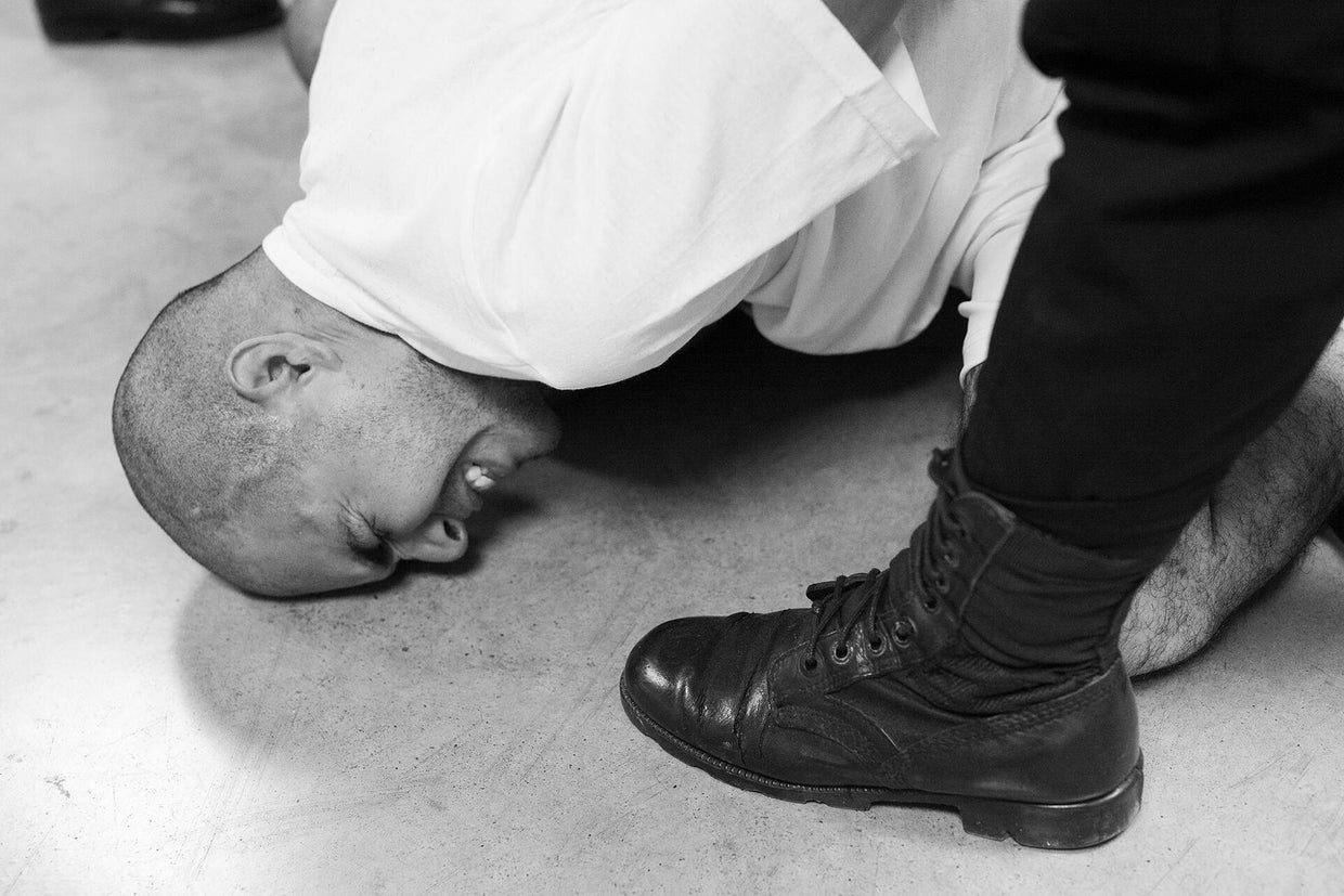Guards at the Terrorism Confinement Center force Venezuelan inmates to the floor. 