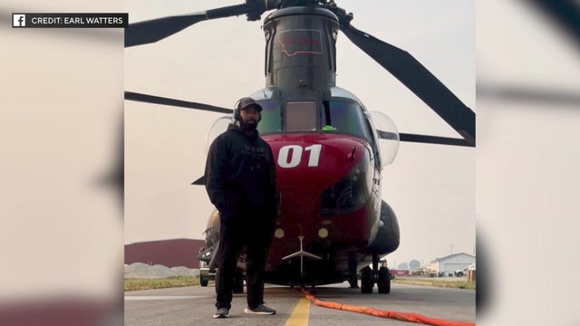 Sean Johnson stands in front of a helicopter.