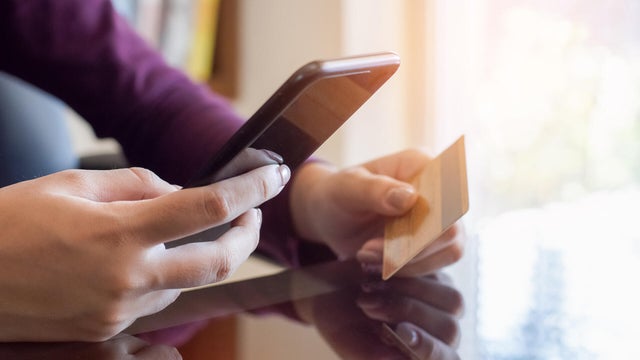 Female holding credit card making online payment, closeup view 