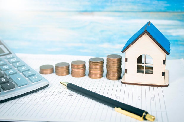 paper, calculator, house and coins on the table 