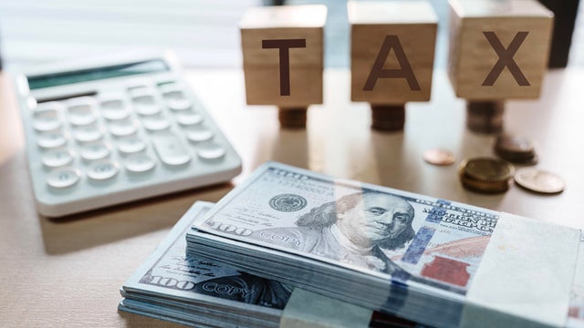 Tax text written on wooden block with stacked coins 