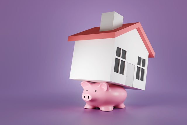 Flattened pink piggy bank carry a toy house on its back on a purple background. Illustration of the concept of the burden of mortgage loans and heavy debt 