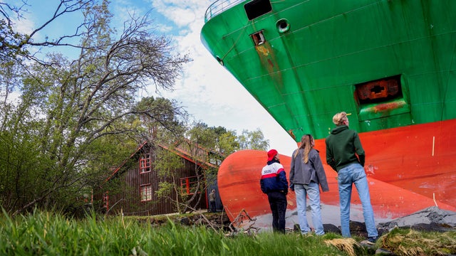People stand near a container ship, which almost hit a house, in Trondheim 