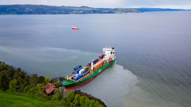 An aerial view shows a 443-foot-long container ship by the shore in the Trondheimsfjord outside Byneset by Trondheim, Norway, on May 22, 2025, after it ran aground, almost hitting a house.