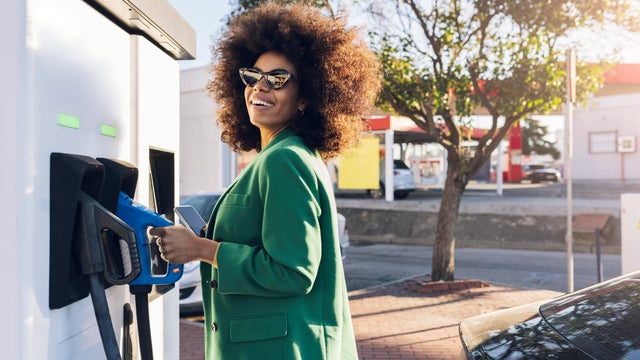Happy businesswoman with fuel pump at gas station 