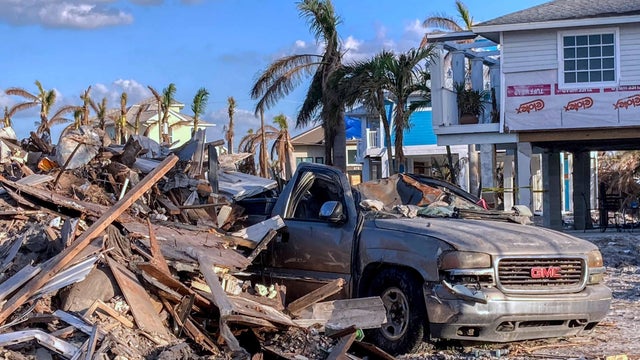 A destroyed truck is seen near a pile of debris in Fort 