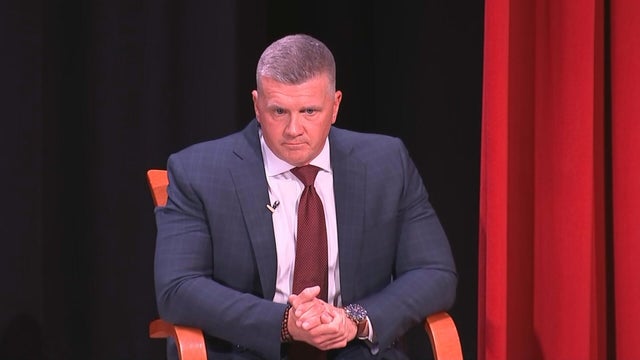 Abram Lucabaugh sits on stage at a meeting 