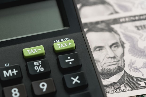 Closed up shot of TAX minus / plus buttons with text TAX RATE on calculator with background of US Dollar banknotes, United States government tax calculation 