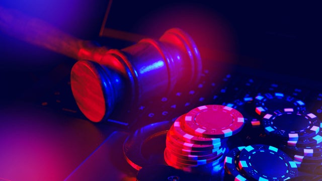 Gavel, Handcuffs, and Poker Chips on a Laptop Keyboard in a Dark Room 