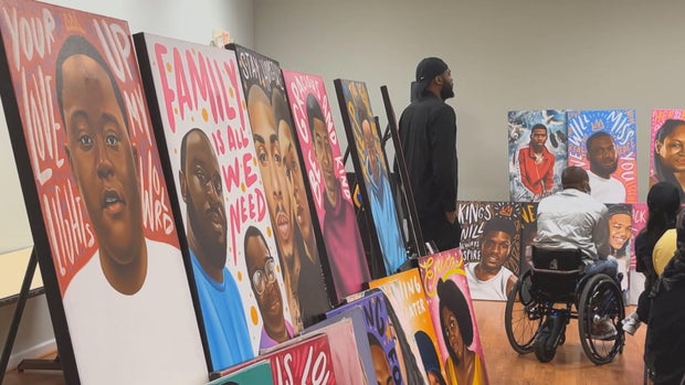 Portraits are displayed around the room, family and loved ones look at the art 
