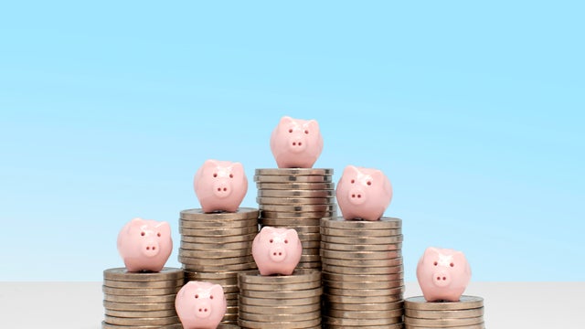 Savings concept - 7 piggy banks on 7 piles of US nickel coins 