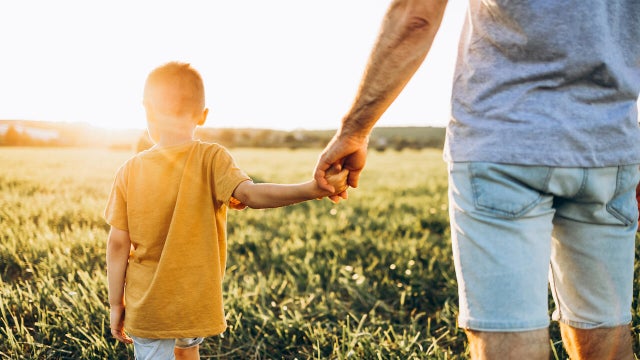 Dad and son walk together holding hands 