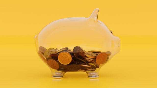 See Through Transparent Glass Piggy Bank With Coins on Blue Yellow 