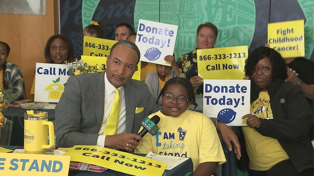 Ukee Washington is in the phone bank talking to a child wearing an Alex's Lemonade Stand shirt 