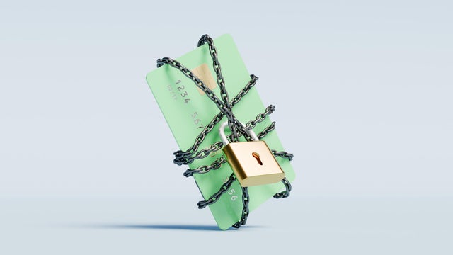 Green credit card wrapped in a chain with a lock 