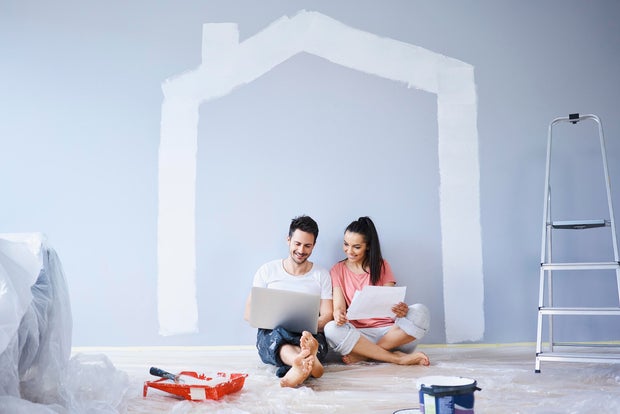 Couple sitting in new apartment using laptop 