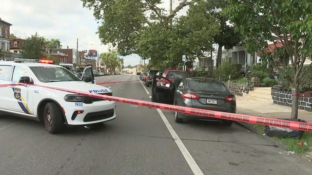 Scene photo shows police tape, police car and a gray sedan with the door open 