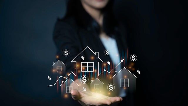 businesswoman holding virtual real estate icons and financial graphs over her hand to illustrate housing market trends and investment growth 
