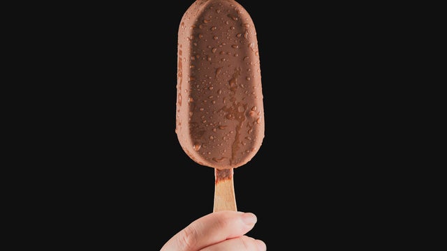 Hand holding a chocolate ice cream on a stick 