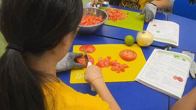 A student cuts up a tomato during a cooking lesson 