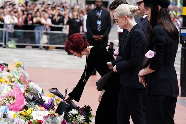 Sharon Osbourne lays flowers as she and family members view messages and floral tributes left at the Black Sabbath Bridge bench on Broad Street in Birmingham, England, in memory of Black Sabbath frontman Ozzy Osbourne, July 30, 2025. 