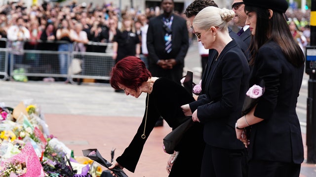 Sharon Osbourne lays flowers as she and family members view messages and floral tributes left at the Black Sabbath Bridge bench on Broad Street in Birmingham, England, in memory of Black Sabbath frontman Ozzy Osbourne, July 30, 2025. 