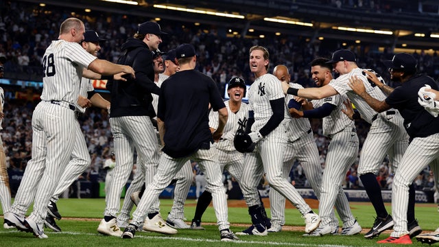 Ryan McMahon #19 of the New York Yankees is mobbed by his teammates after his eleventh inning game winning base hit against the Tampa Bay Rays at Yankee Stadium on July 30, 2025 in New York City. 