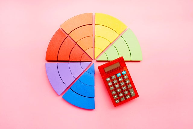 High angle view of a pie chart made of colorful building blocks and red calculator on pink background 