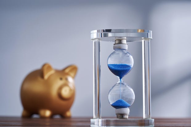 gold piggy bank and hourglass on the table.Time is money 