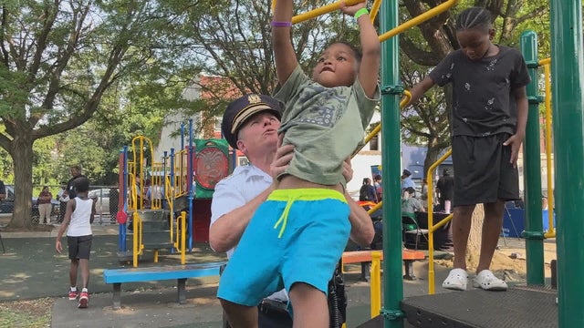 A police officer helps a little boy with the monkey bars 