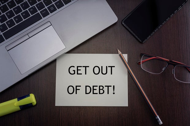 Get out of debt card. Top view of office table desktop background with laptop, phone, glasses and pencil with card with inscription get out of debt. Business concept. 
