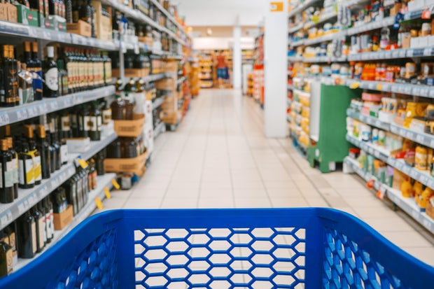 First person view of a shopping cart in the aisle of a supermarket. 