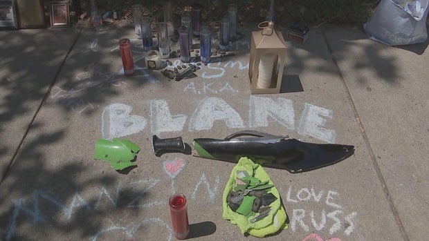 A makeshift memorial for "Blane" includes candles and pieces of his motorcycle 