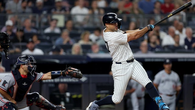 Giancarlo Stanton #27 of the New York Yankees hits a solo home run in the fifth inning as Mickey Gasper #11 of the Minnesota Twins defends at Yankee Stadium on August 12, 2025 in the Bronx borough of New York City. 