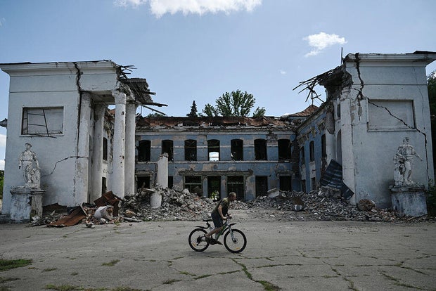 A man rides his bicycle past a destroyed building in Druzhkivka, Donetsk region, on Aug. 15, 2025. 